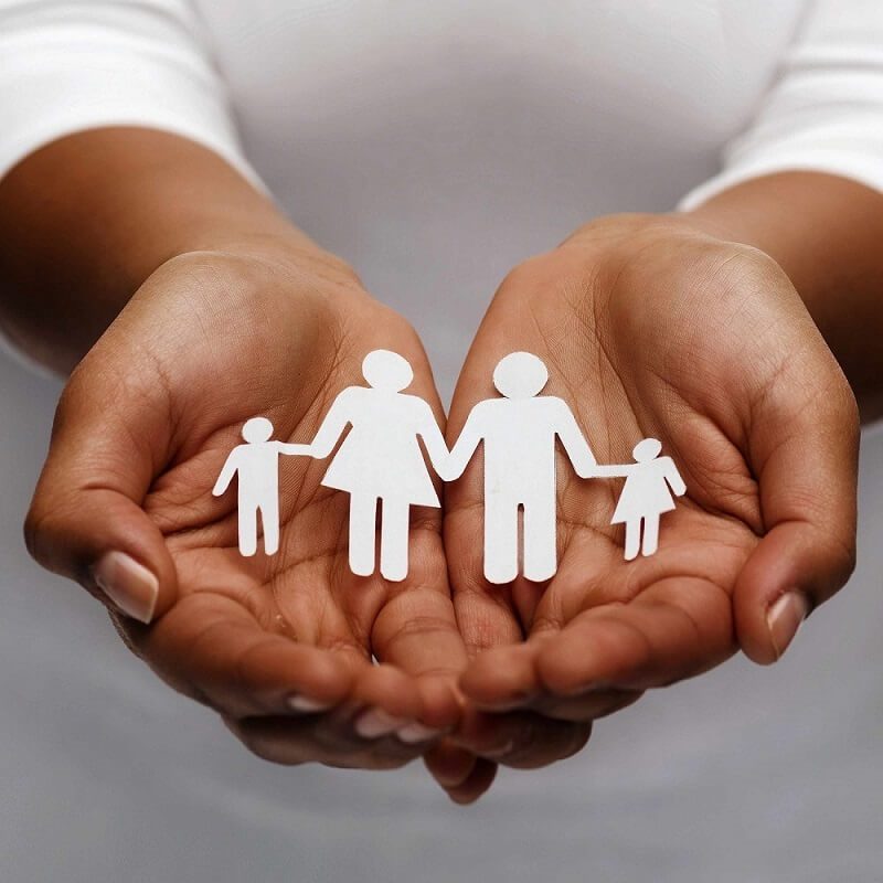 Hands holding a paper cut-out of a family